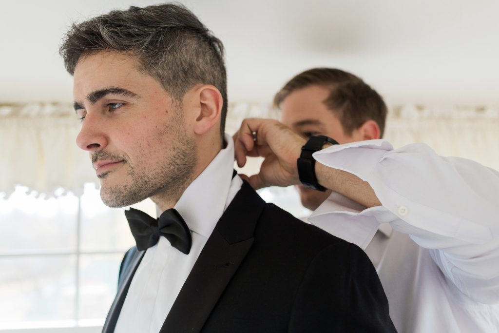 Photo of groom getting ready with groomsman