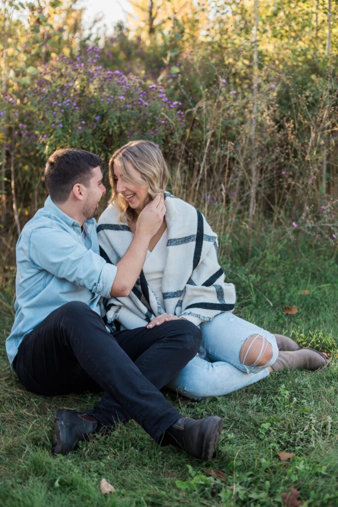 engaged couple snuggling in grass