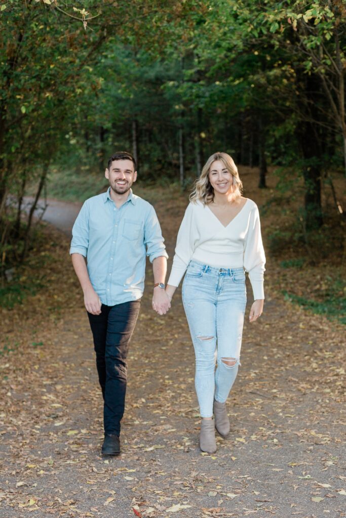 Engaged couple walking hand in hand in fall park session