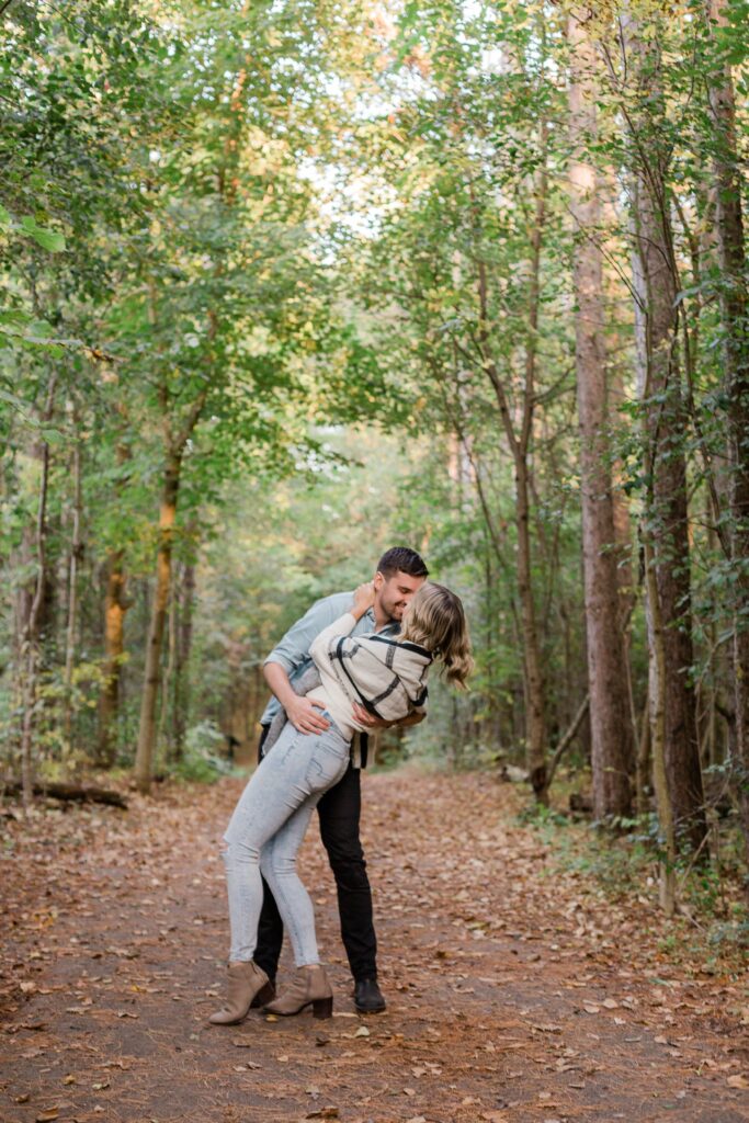 couple dip kissing in fall tree line