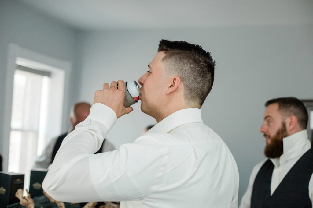 groom drinking beer while getting ready