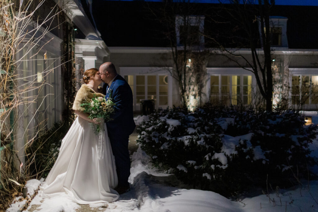outside nighttime wedding photo of bride and groom kissing