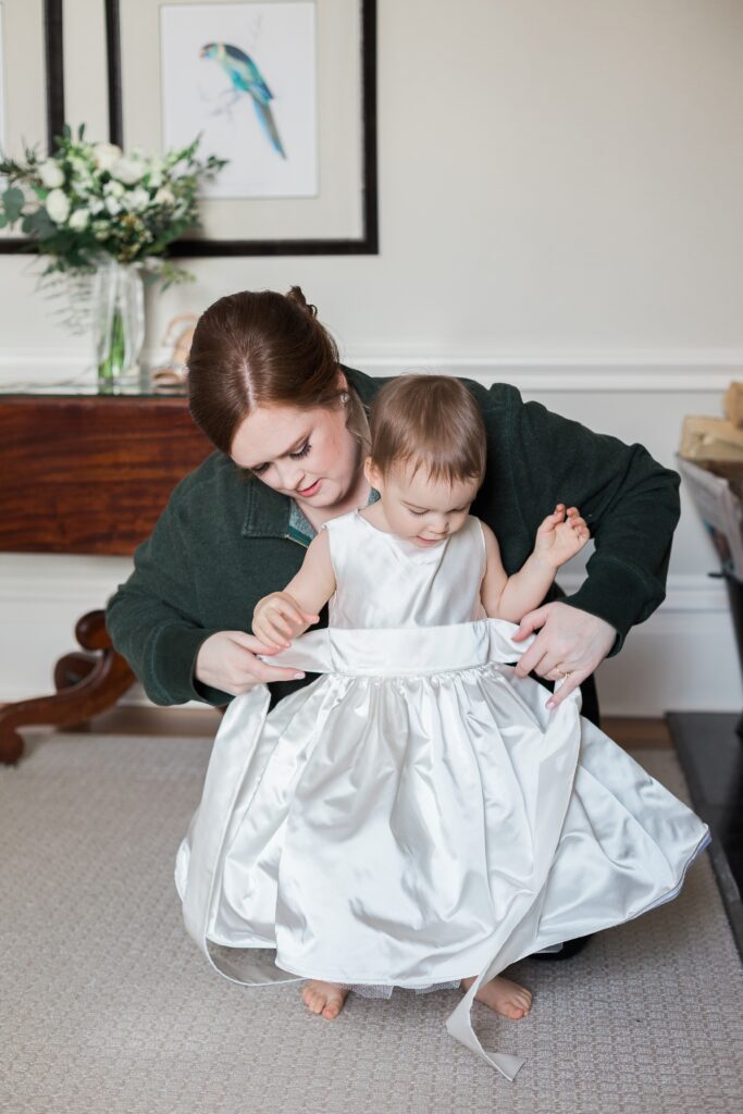 bride getting daughter into flower girl dress