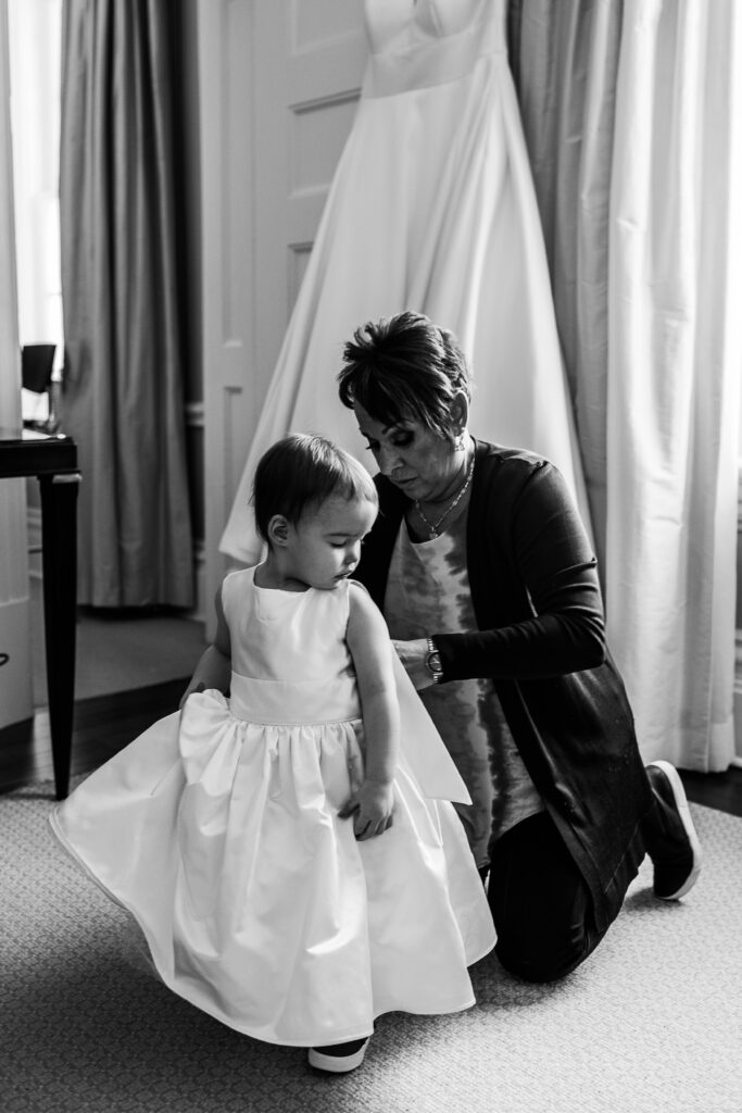 Flower girl getting dressed with grandma in black and white