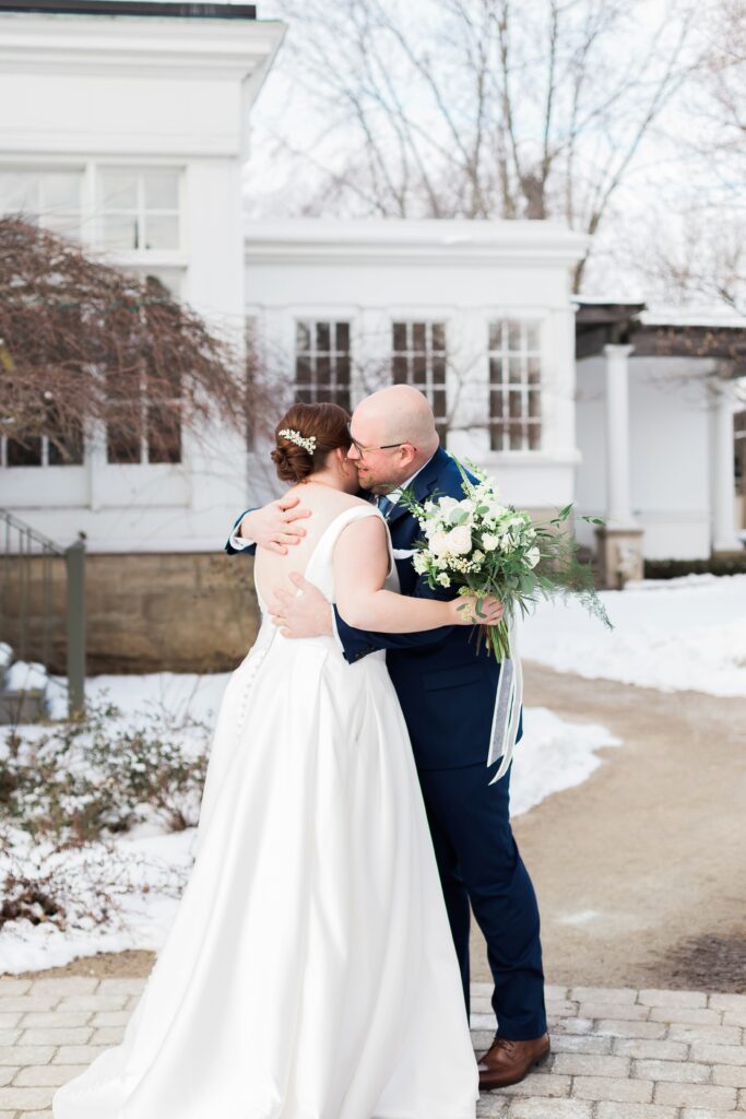 bride and groom hug during first look at Langdon Hall in snow