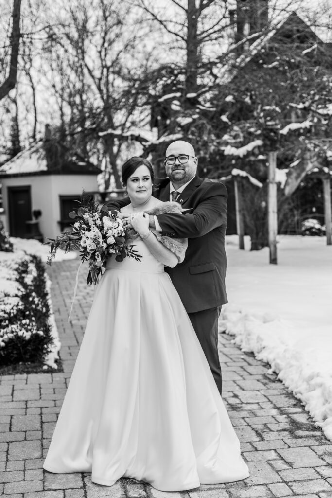 full body portrait of bride and groom in black and white hugging
