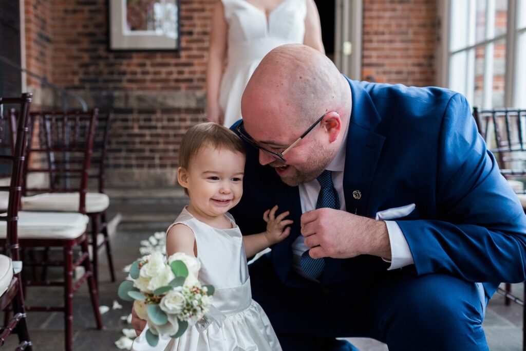 flower girl with big smile on her face hugging dad intimate