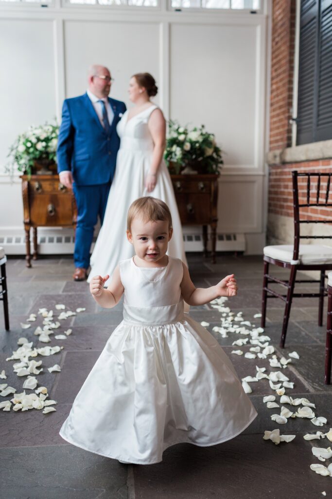 flower girl with bride and groom in background