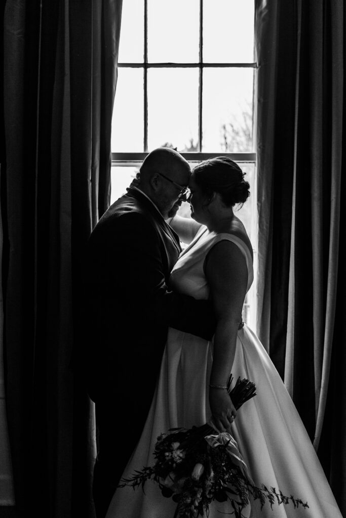 black and white silhouette of bride and groom in front of window