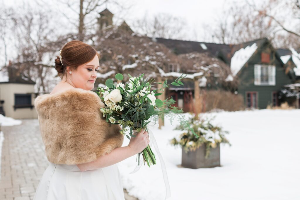 bride smelling floral bouquet outside in the snow