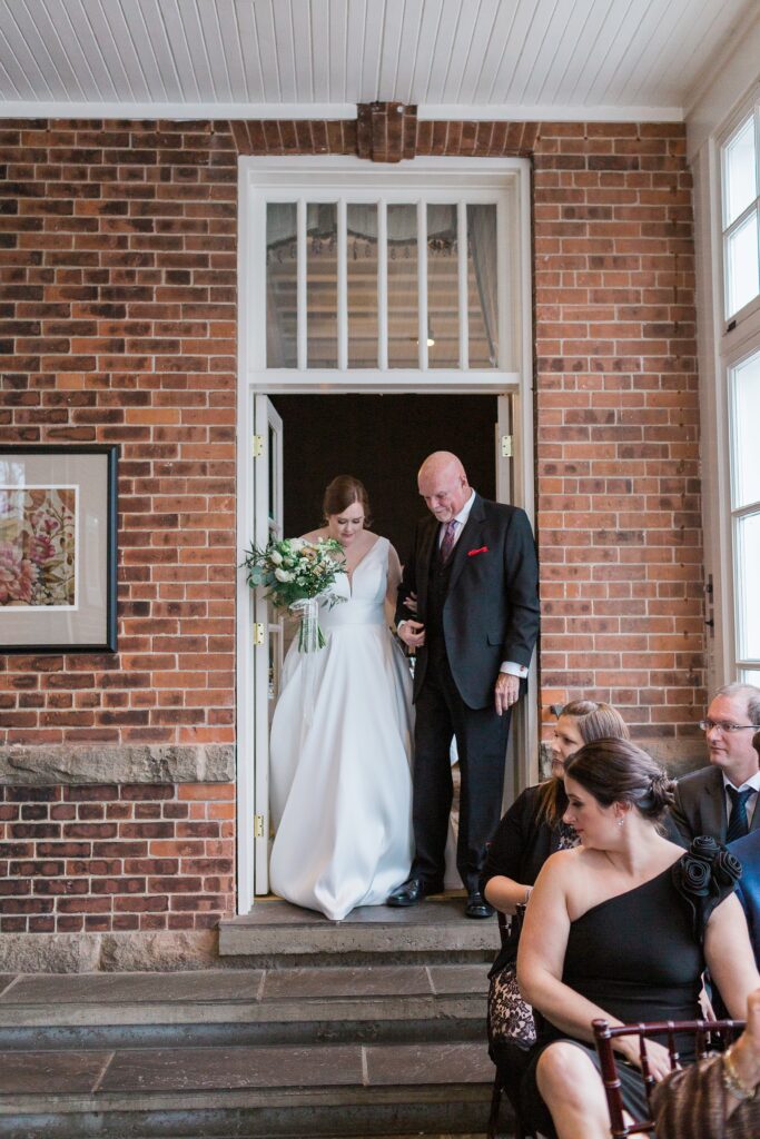 bride and dad enter ceremony room and walk aisle