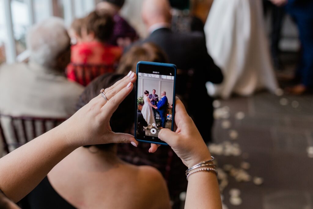 photo of a cell phone taking a photo of wedding couple at their ceremony