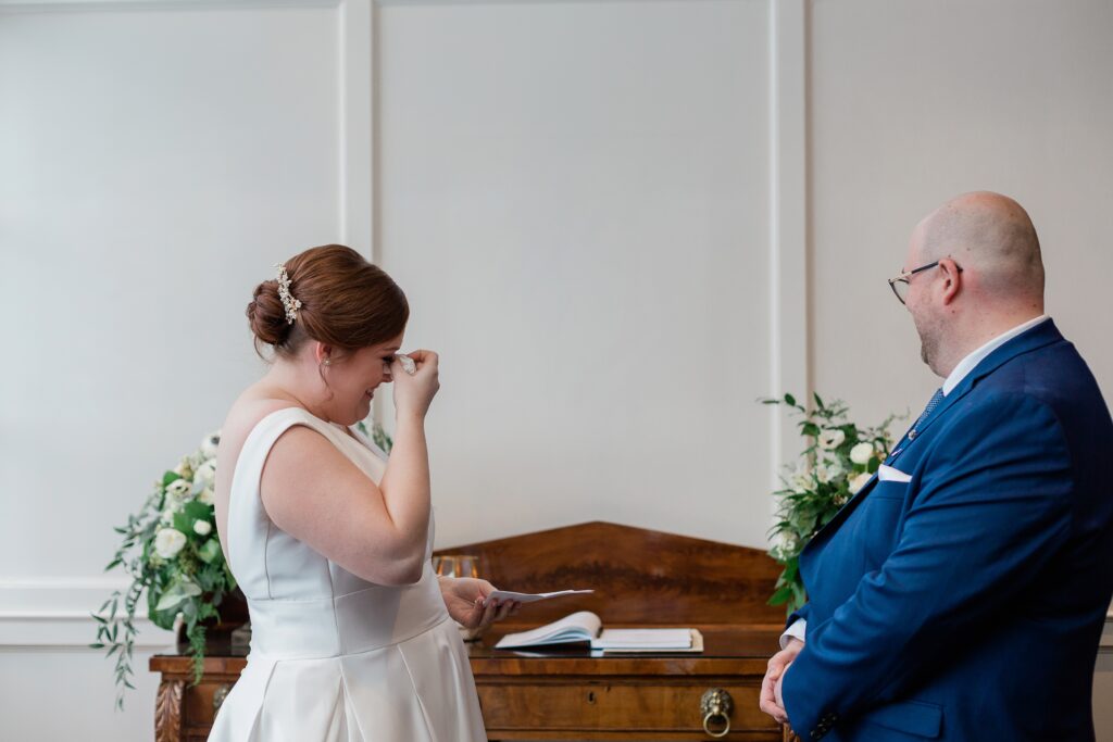 bride laughing while wiping tears away during ceremony