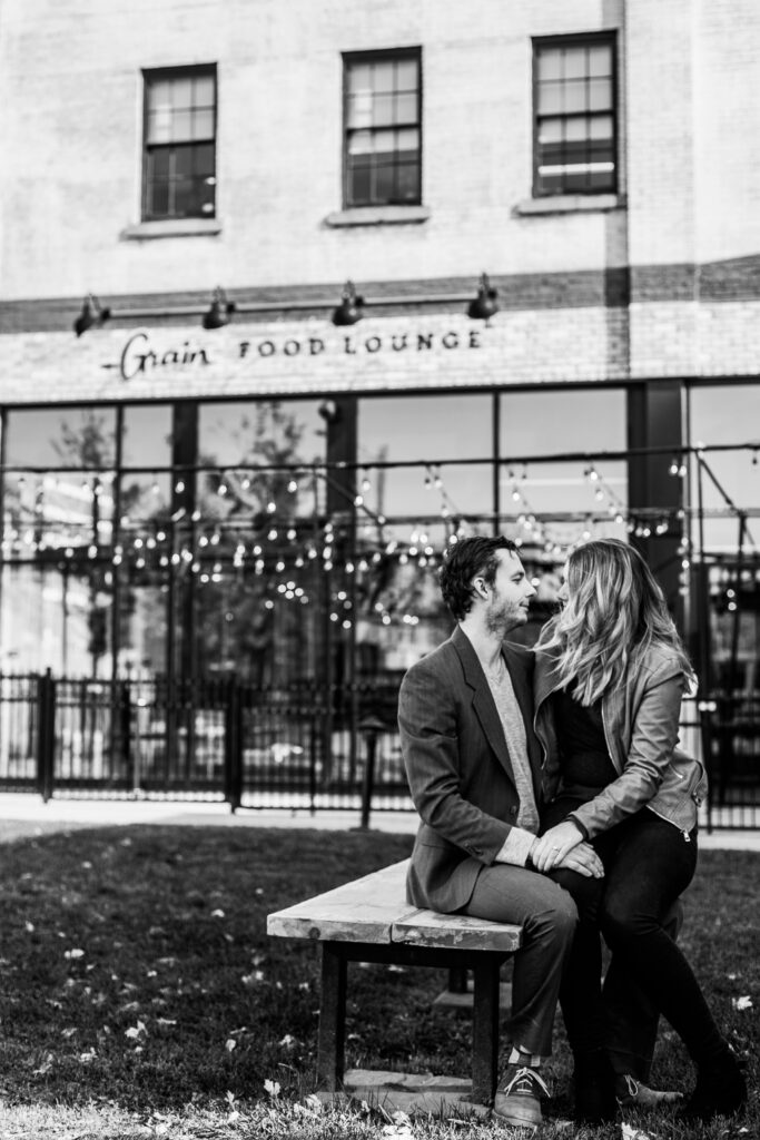 engaged couple with bride to be sitting on fiances lap in black and white