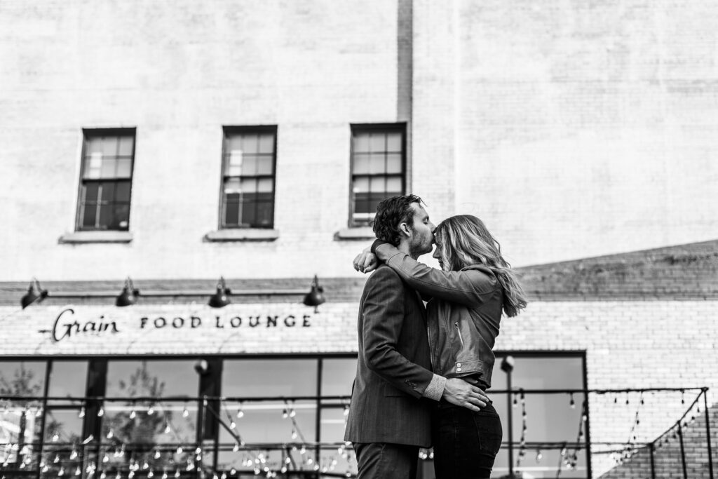 black and white of groom kissing bride to be on forehead 