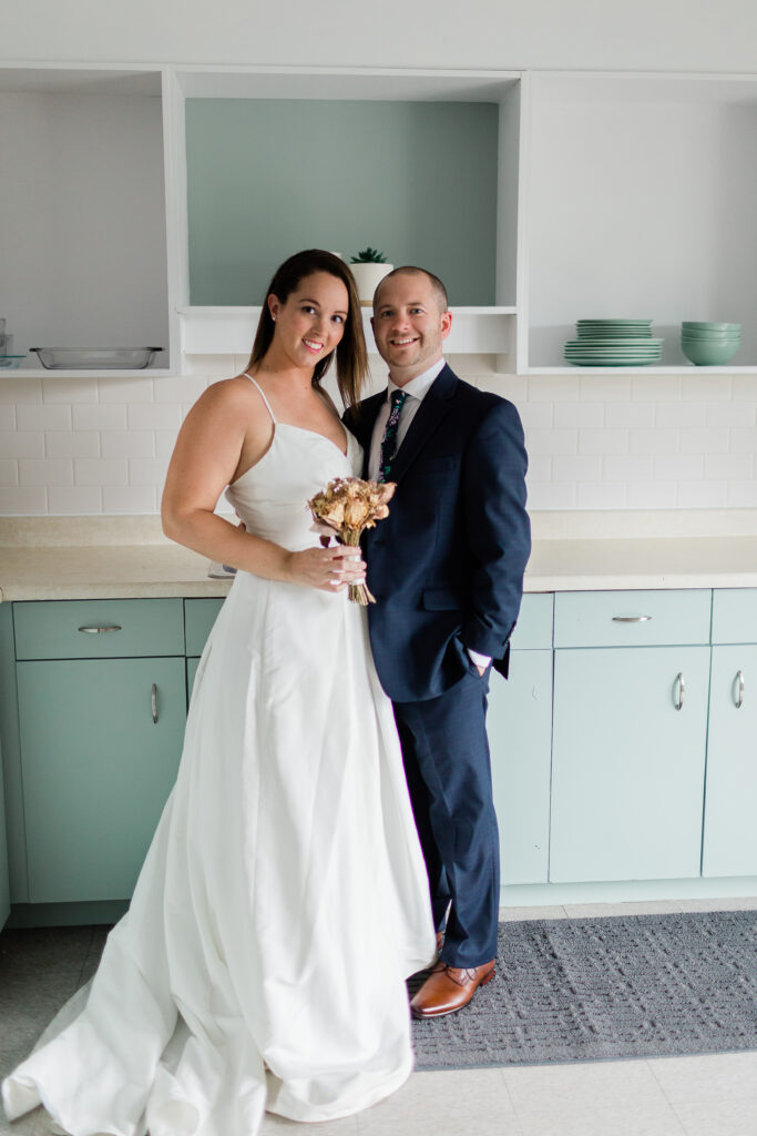 bride and groom in kitchen full body looking at camera