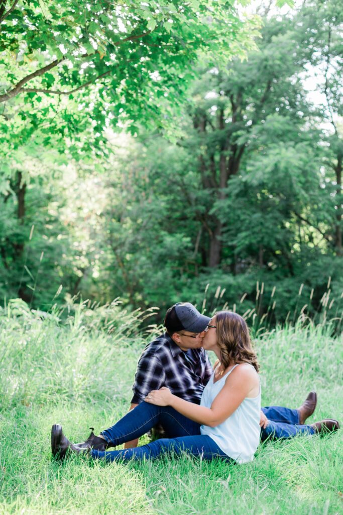 Couple kissing in field for engagement photos.