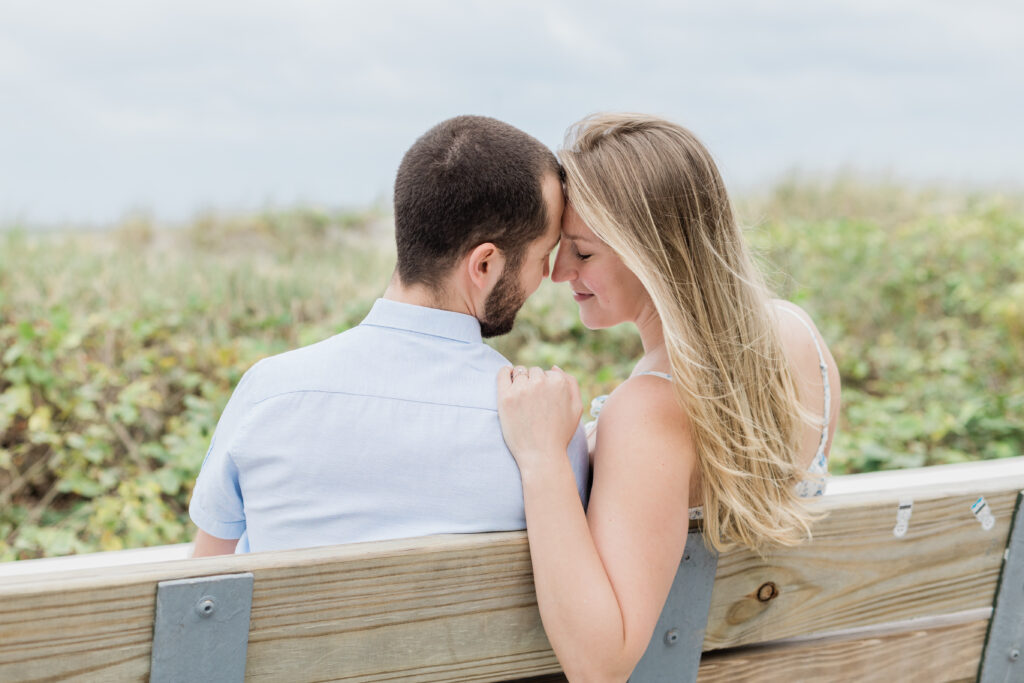couple snuggled up on beach park for their engagement session in Florida