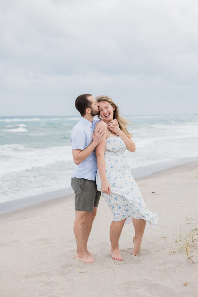 Couple playing in sand in Boca Raton, Florida during their engagement session