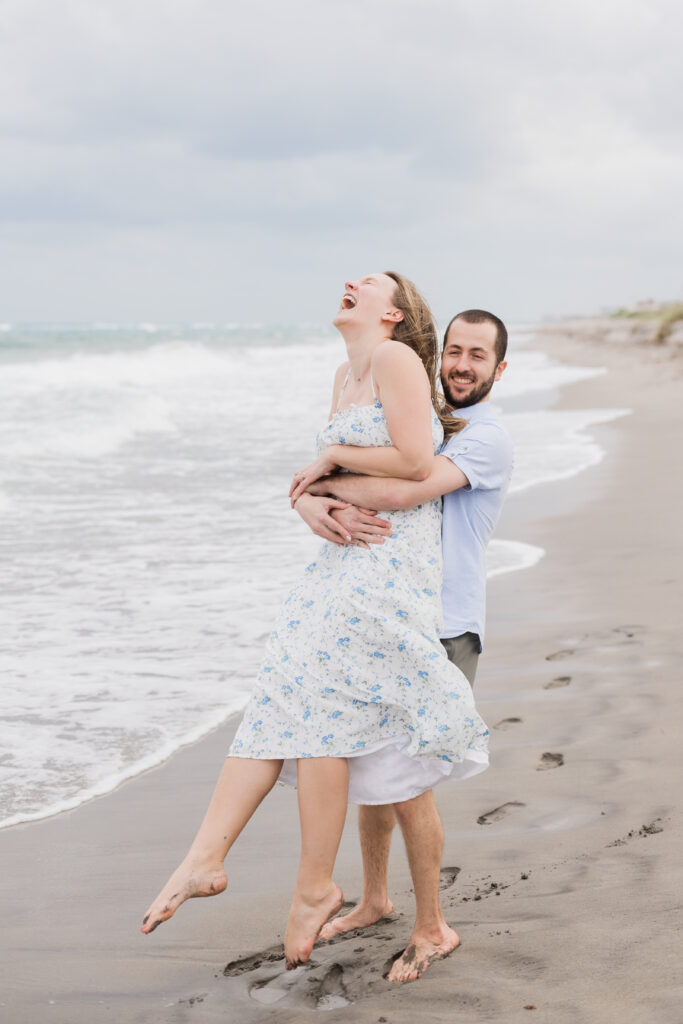fiance spinning woman in a circle on the beach in Florida for their engagement session