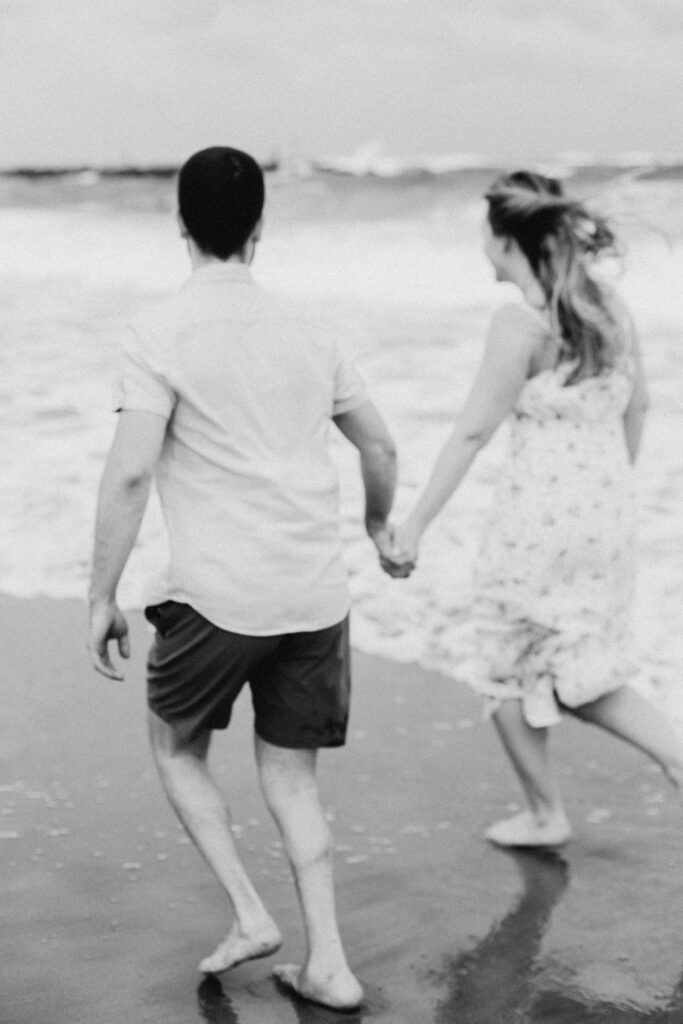 blurry black and white image of couple running along beach in Florida 