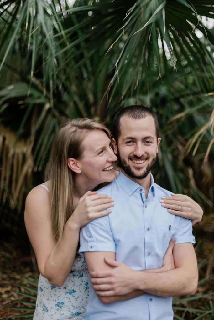 woman hugging fiance from behind smiling at him during their destination engagement session