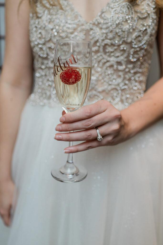 bride holding a glass of champagne showing off her diamond engagement ring on her rainy wedding day