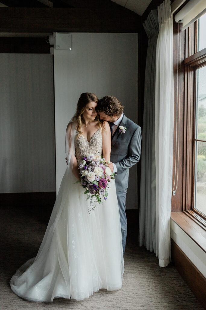 Bride and Groom at Whistle Bear Golf Club snuggled up by the window on their rainy wedding day