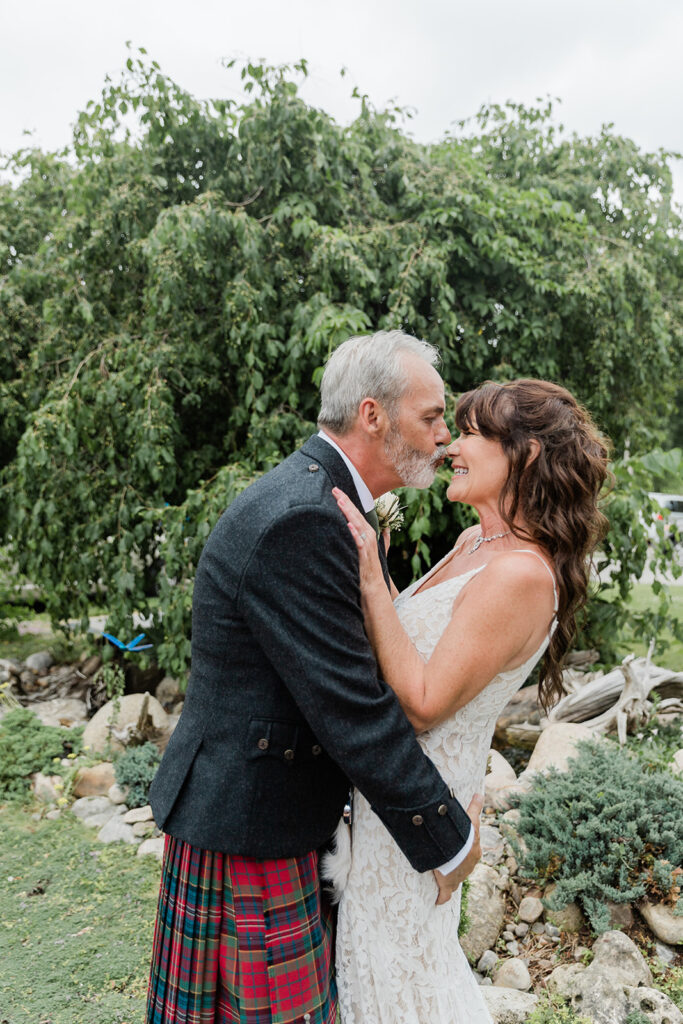 groom kissing brides nose in the garden after their backyard wedding ceremony