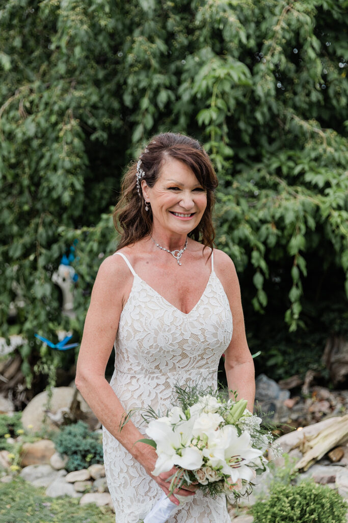bride looking at the camera smiling with her bridal bouquet in the garden