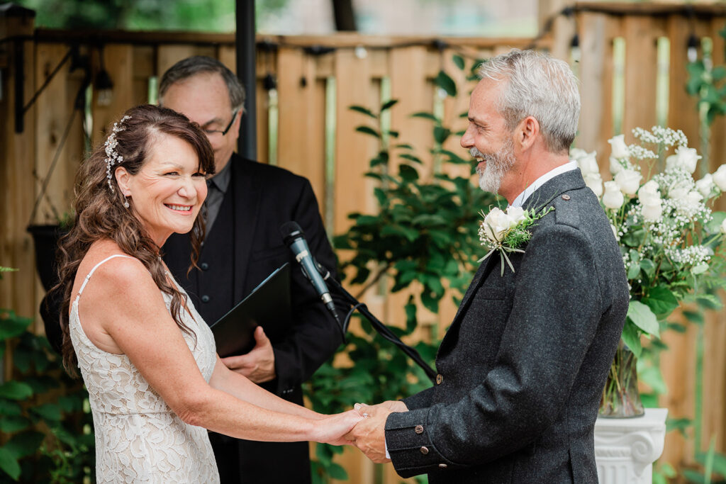 Couple in their backyard summer wedding smiling during their ceremony