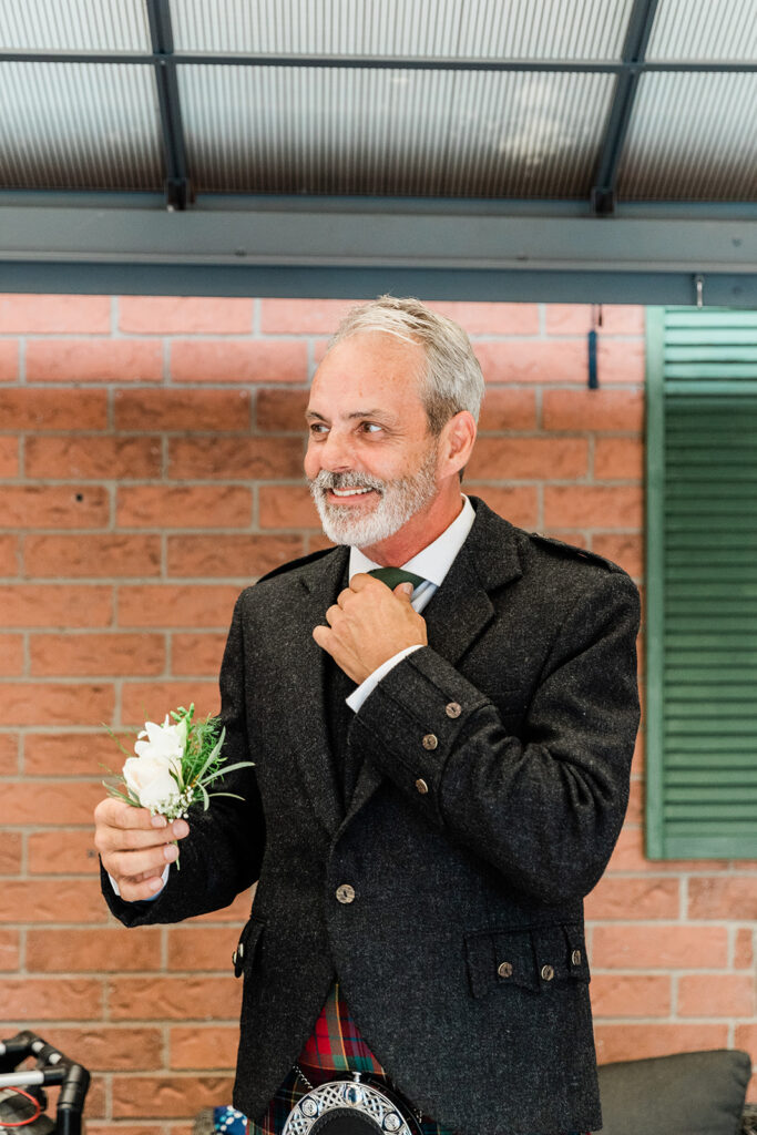 Groom preparing for his ceremony by putting on his boutonniere