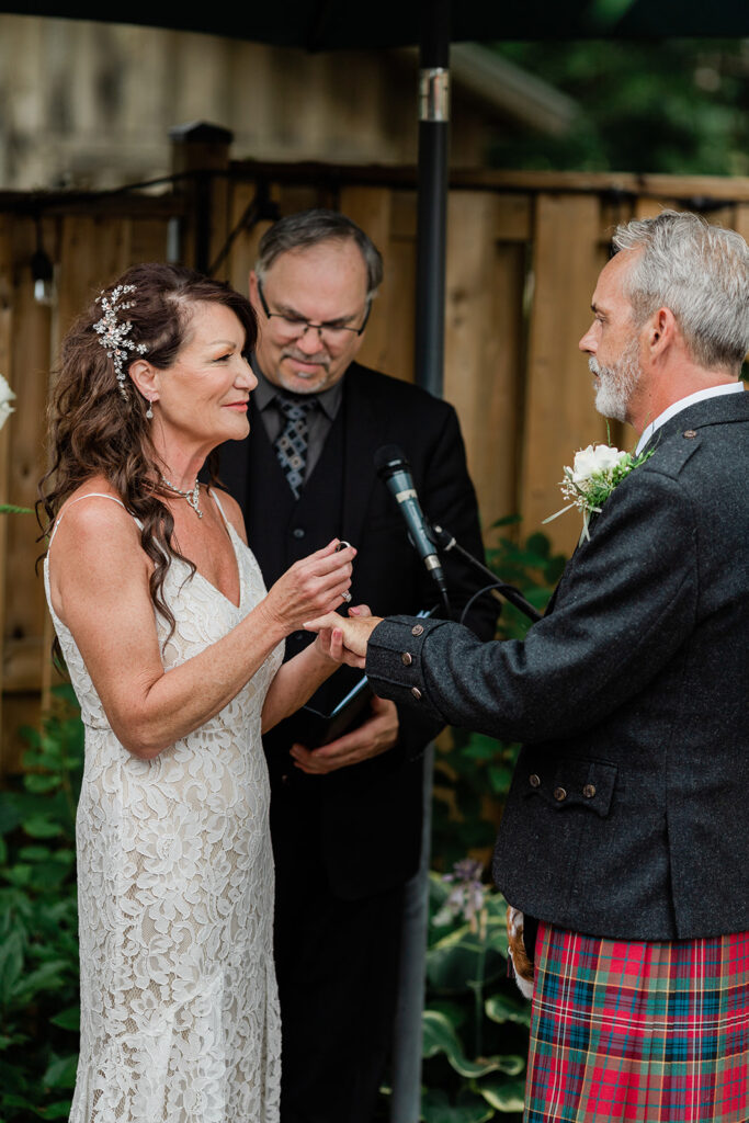 bride placing ring on her grooms hand during their summer ceremony
