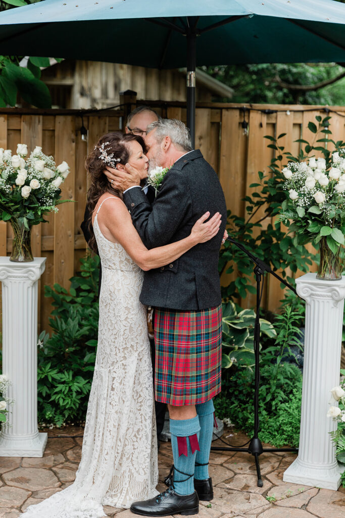 couples first kiss during their backyard summer wedding ceremony