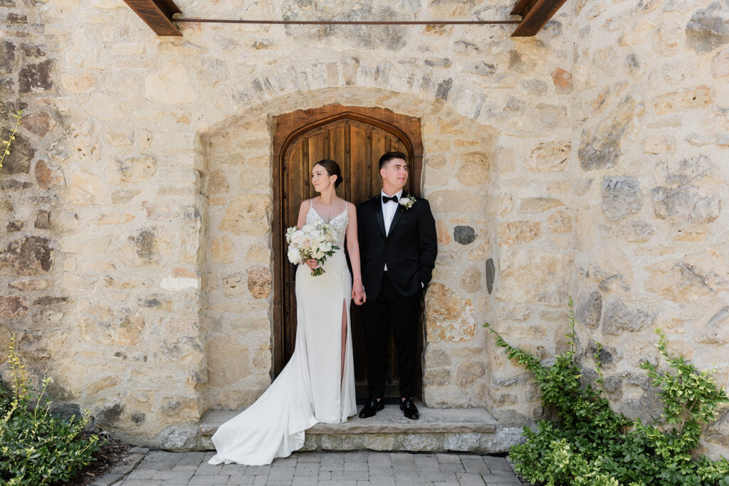 bride and groom standing on door stoop holding hands