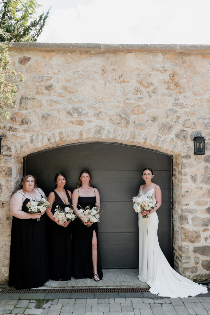 bride and bridesmaids standing in front of garage door 