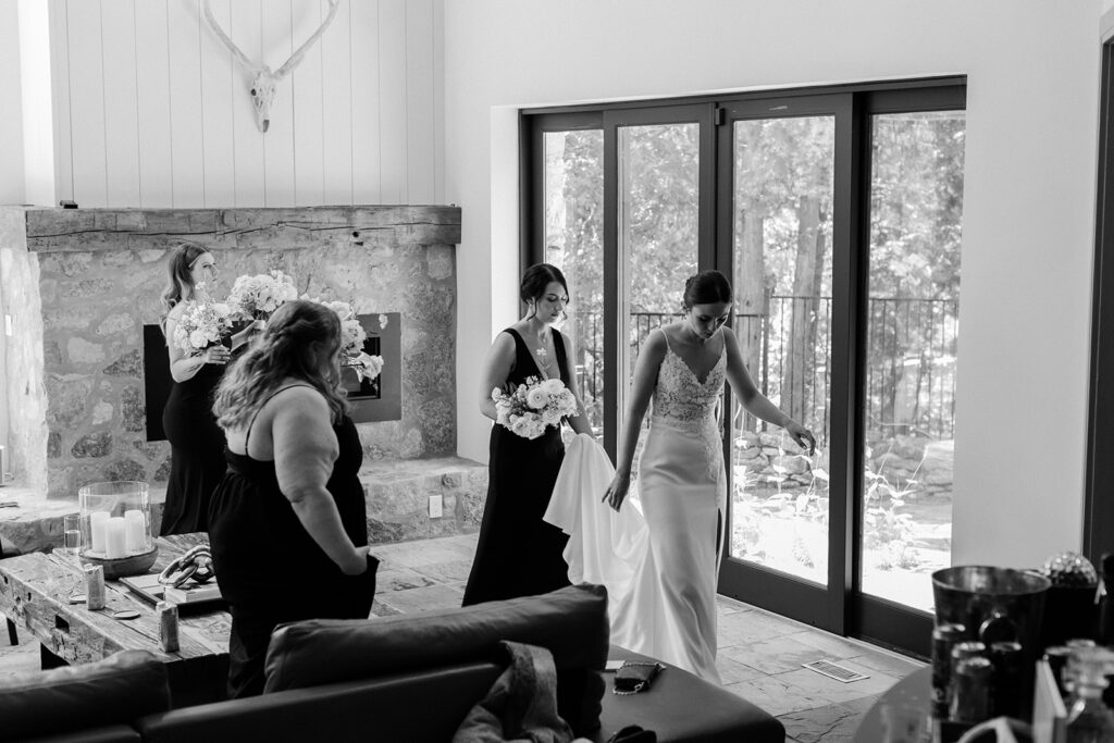 bridesmaids walking out of living room carrying brides train