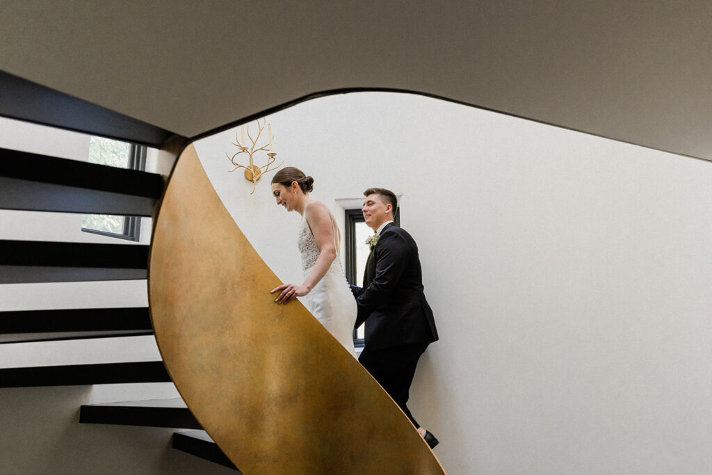 bride and groom holding hands walking up spiral staircase