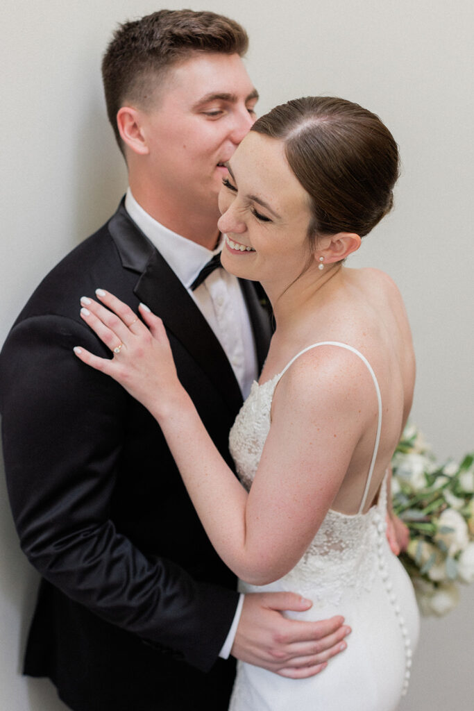 bride and groom giggling while groom kisses her cheek