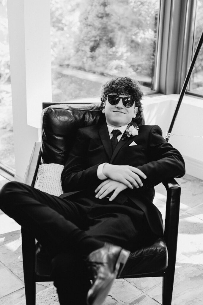 groomsman lounging smiling in chair wearing sunglasses
