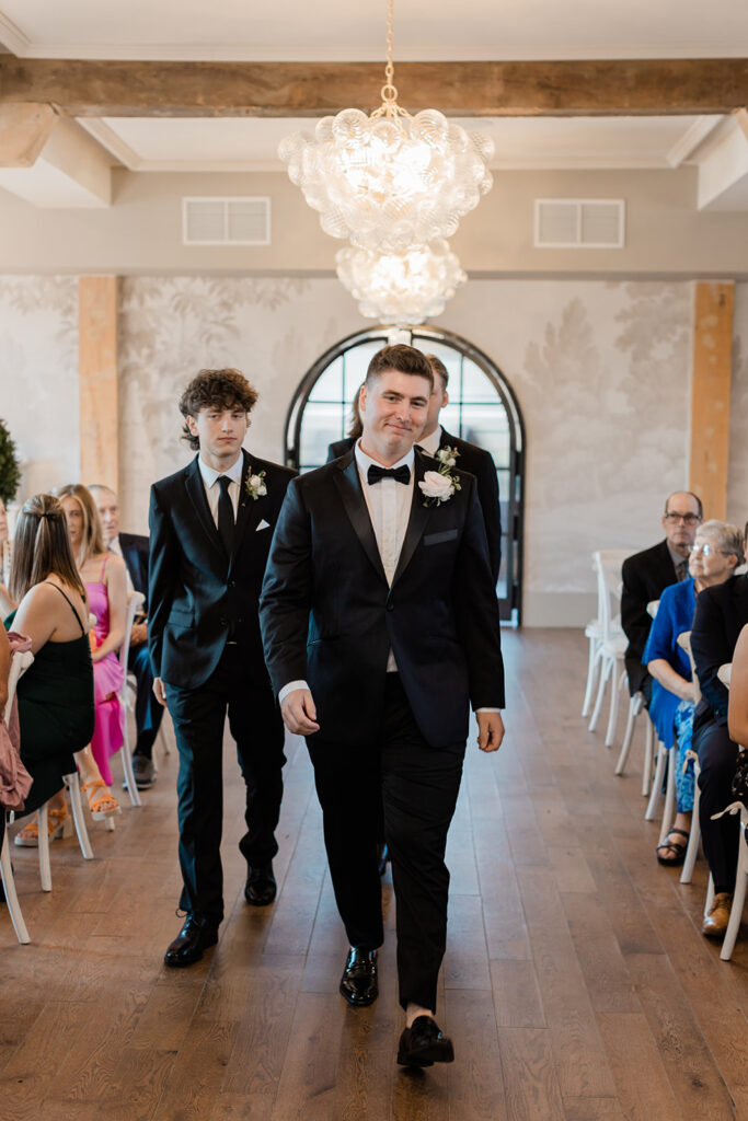 groom walking into his ceremony with his groomsmen