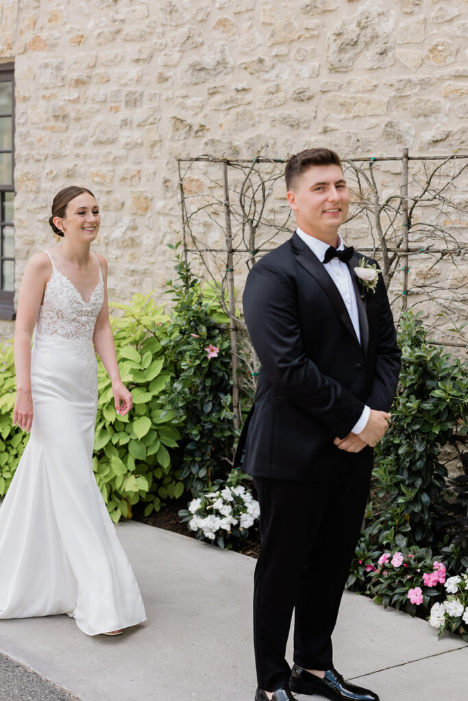 bride walking up behind groom during their first look at Elora Mill Hotel and Spa