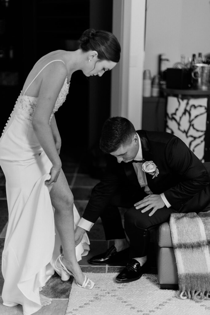 groom helping bride put on her shoe