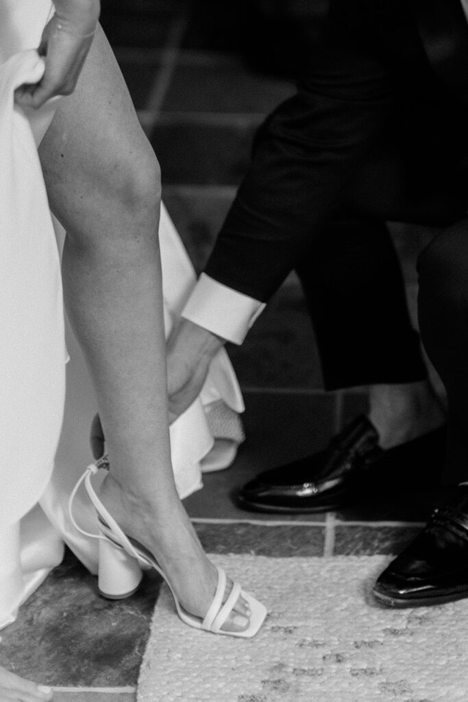 close up photo of groom helping to put on his brides shoe