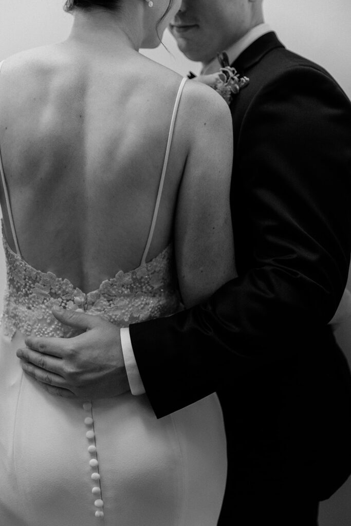 black and white close up photo of grooms hands on the lower back of bride