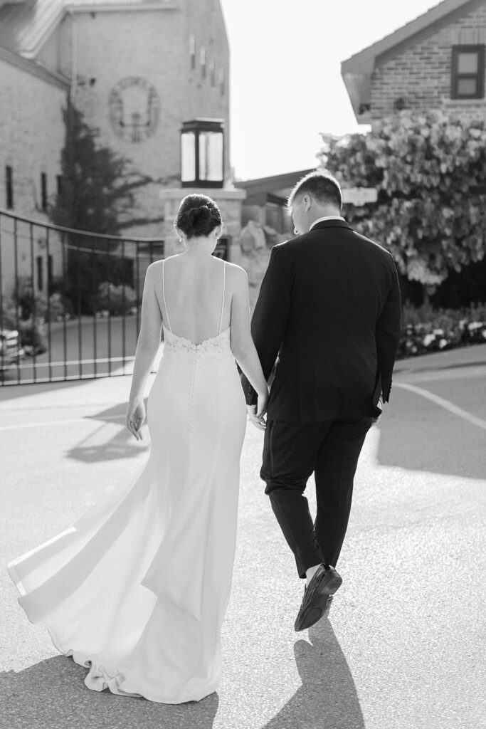 black and white photo of couple at their Elora Mill Wedding walking in front of gates