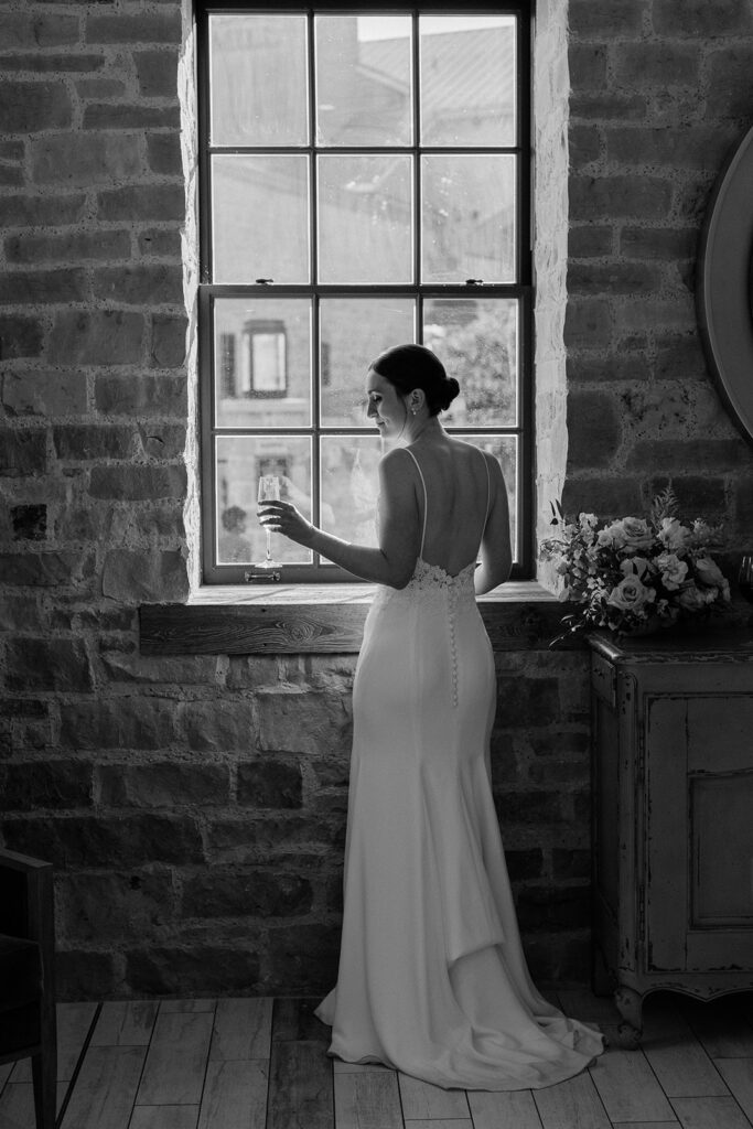bride in black and white photo holding champagne at her Elora Mill Wedding