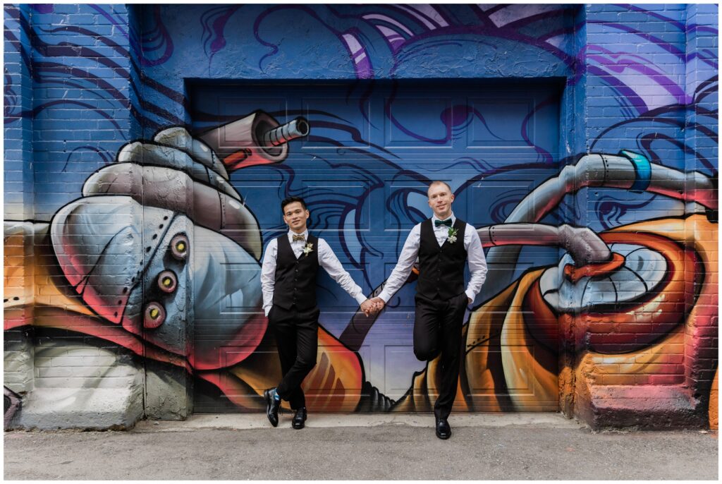 wedding couple holding hands in front of graffiti wall in downtown wedding