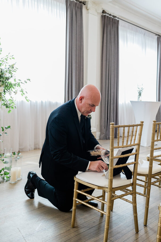 Groom placing photo and flower on memorial chair at Walper Hotel Wedding ceremony